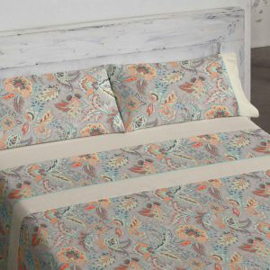 Juego de sábanas moderno y juvenil conseguido a base de reinterpretar de forma creativa un modelo clásico ornamental. Sobre un fondo gris se dibuja un diseño colorista en el que están presentes grises, naranjas y azules. Una sábana juvenil pese a su raiz clásica. La sábana bajera ajustable es en liso beige clarito, al igual que la aplicación que adorna los embozos. Ribete a conjunto